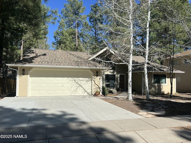 view of front of house featuring fence, concrete driveway, a shingled roof, and a garage