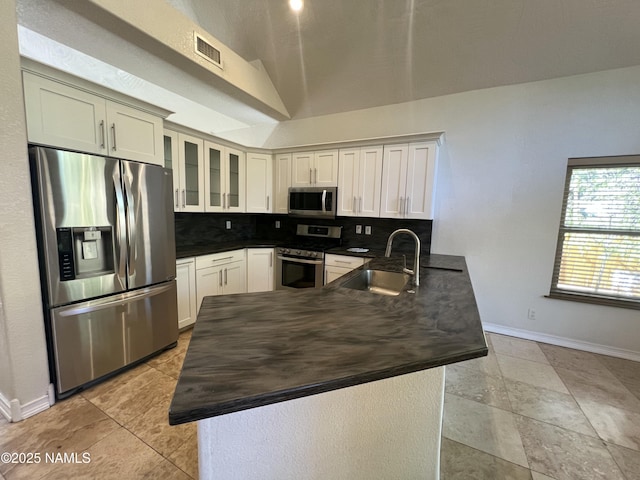 kitchen featuring tasteful backsplash, a sink, stainless steel appliances, baseboards, and a peninsula