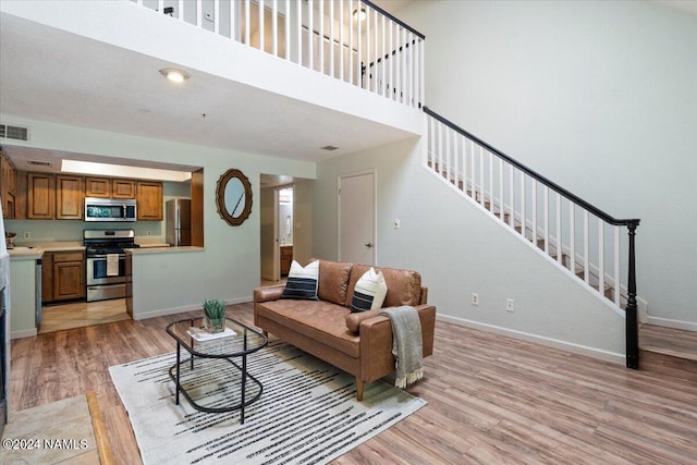 living room with light hardwood / wood-style floors and a high ceiling