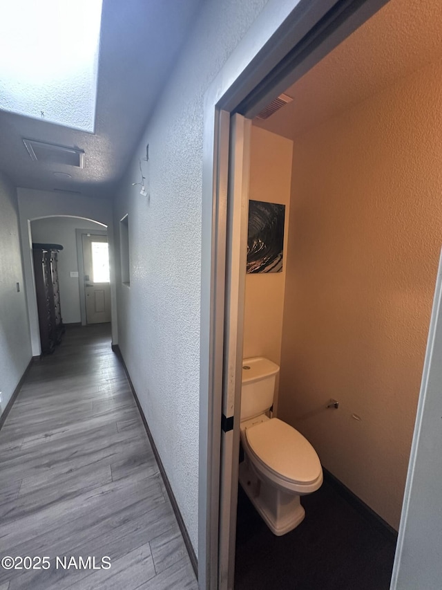 255 S Beech Dr, Flagstaff, AZ 86004 - corridor featuring arched walkways, a textured wall, baseboards, and wood finished floors