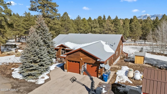 view of front of house featuring a wooded view, driveway, a garage, a mountain view, and metal roof