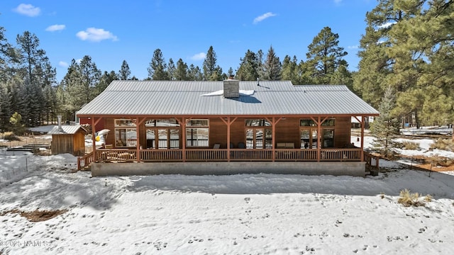 snow covered property with metal roof and a chimney