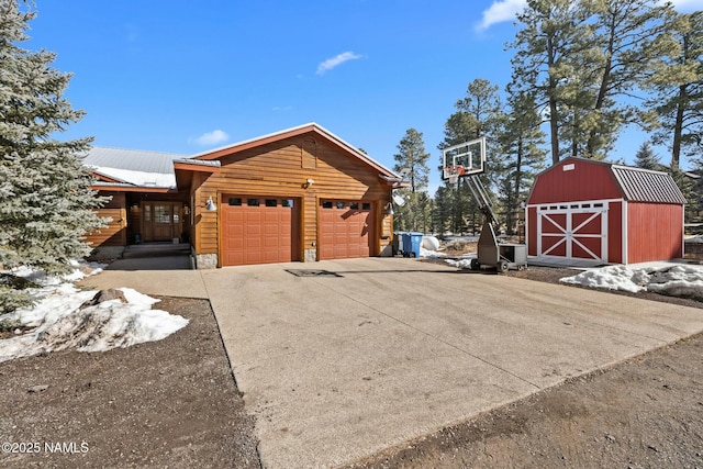 view of side of property featuring a barn, an outdoor structure, an attached garage, and driveway