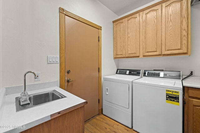 washroom featuring separate washer and dryer, cabinet space, light wood-style floors, and a sink