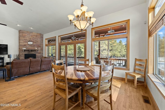 dining room with visible vents, baseboards, lofted ceiling, a fireplace, and light wood-style floors