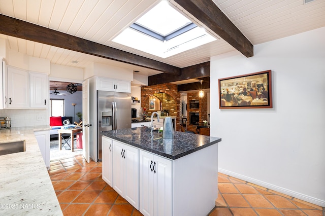 1125 Trails End Dr, Sedona, AZ 86336 - kitchen featuring a skylight, stainless steel refrigerator with ice dispenser, light tile patterned floors, tasteful backsplash, and white cabinetry
