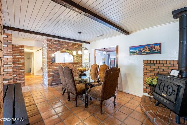 1125 Trails End Dr, Sedona, AZ 86336 - dining space with a wood stove, tile patterned floors, wood ceiling with exposed beams, and brick wall