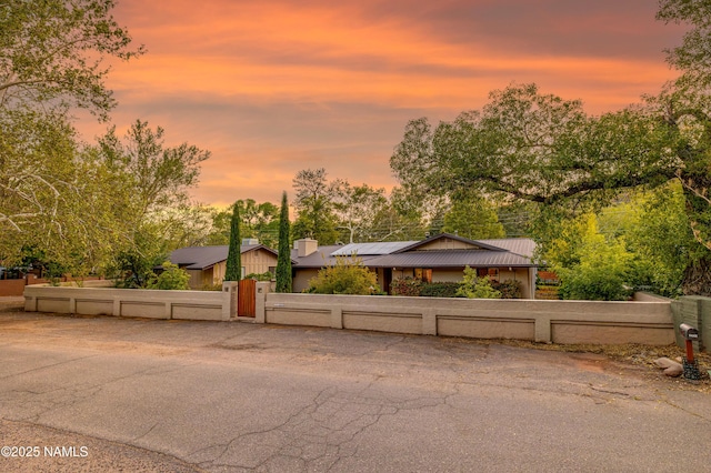 1125 Trails End Dr, Sedona, AZ 86336 - mid-century inspired home featuring a fenced front yard, a gate, solar panels, metal roof, and view of scattered trees