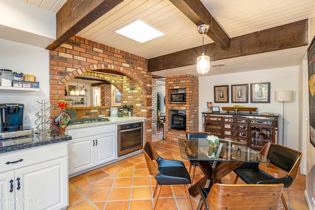 1125 Trails End Dr, Sedona, AZ 86336 - kitchen with appliances with stainless steel finishes, white cabinets, a fireplace, pendant lighting, and brick wall