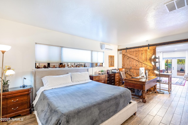 1125 Trails End Dr, Sedona, AZ 86336 - bedroom with a wall mounted air conditioner, wood finished floors, a barn door, and access to outside