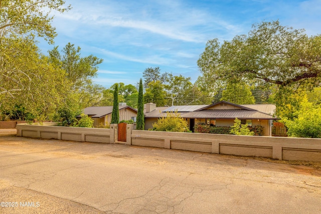 1125 Trails End Dr, Sedona, AZ 86336 - mid-century modern home with a fenced front yard, a gate, solar panels, and metal roof