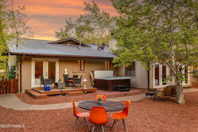1125 Trails End Dr, Sedona, AZ 86336 - back of house at dusk featuring french doors, a hot tub, metal roof, a wooden deck, and stucco siding