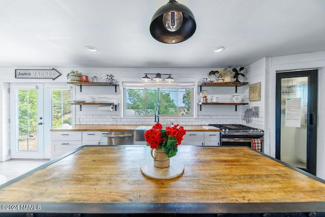 kitchen featuring appliances with stainless steel finishes, white cabinetry, butcher block counters, sink, and backsplash