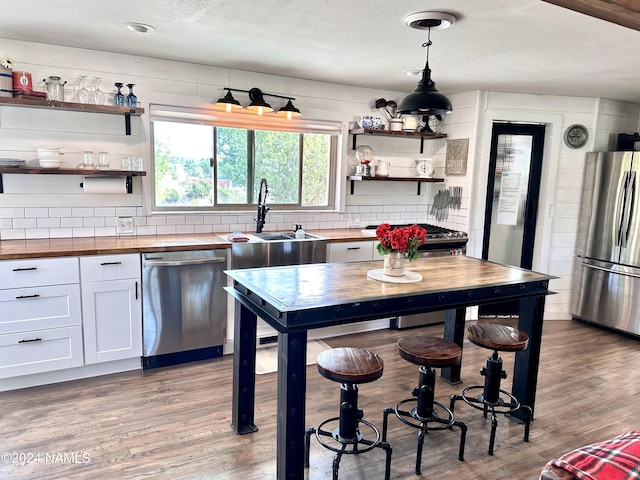 kitchen featuring wood counters, white cabinetry, stainless steel appliances, sink, and light wood-type flooring