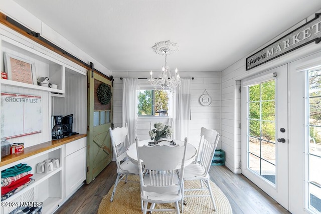 dining room featuring a healthy amount of sunlight, dark wood-type flooring, french doors, and a barn door