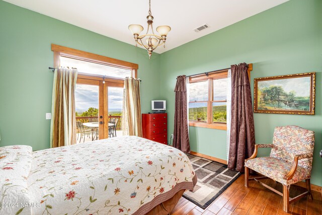 bedroom with wood-type flooring, access to exterior, a notable chandelier, and french doors