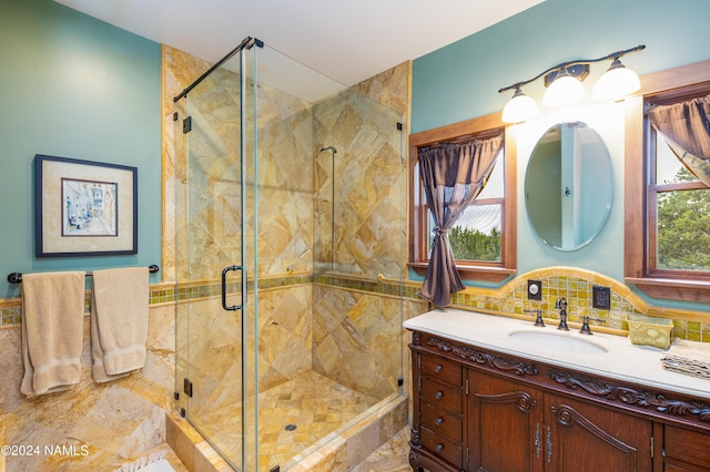 bathroom featuring backsplash, a shower with door, a healthy amount of sunlight, and vanity