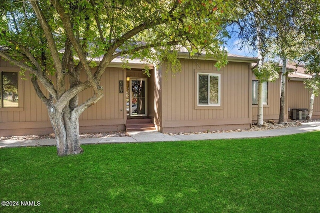 rear view of house featuring a lawn and central air condition unit