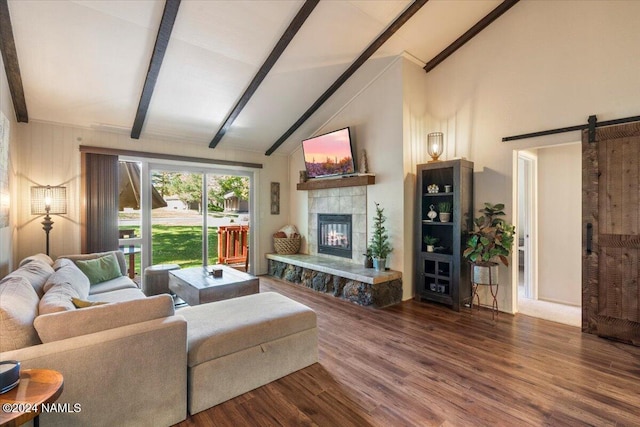 living room featuring a tiled fireplace, a barn door, hardwood / wood-style flooring, and beam ceiling