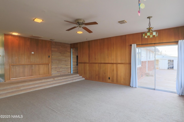 unfurnished living room with wooden walls, carpet floors, and ceiling fan