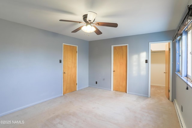 unfurnished bedroom featuring ceiling fan, a baseboard radiator, a spacious closet, and light carpet