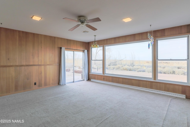 carpeted spare room featuring ceiling fan and a baseboard heating unit