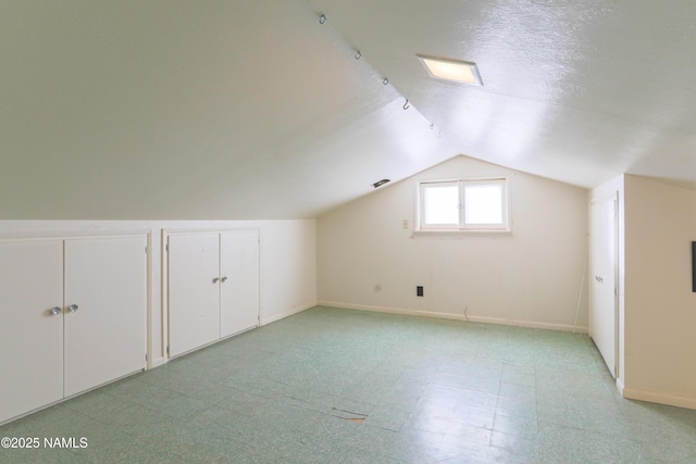 additional living space featuring a textured ceiling and lofted ceiling