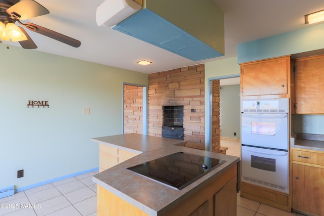 kitchen with a kitchen island, black electric stovetop, double oven, ceiling fan, and light tile patterned floors