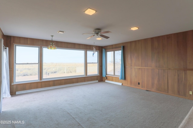 carpeted spare room with ceiling fan and a baseboard heating unit