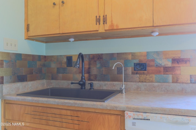 kitchen featuring white dishwasher, sink, backsplash, and light brown cabinetry