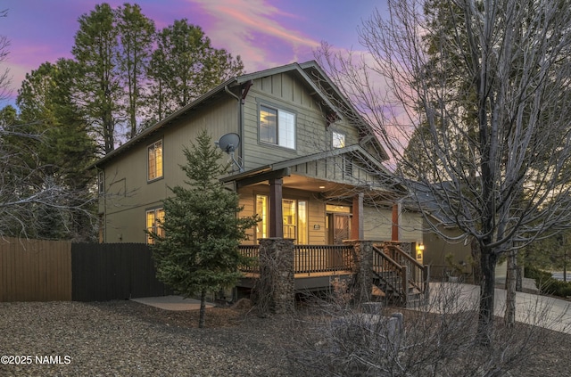 view of front of house featuring covered porch, driveway, and fence