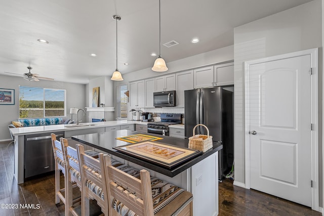 kitchen featuring appliances with stainless steel finishes, sink, hanging light fixtures, kitchen peninsula, and a breakfast bar