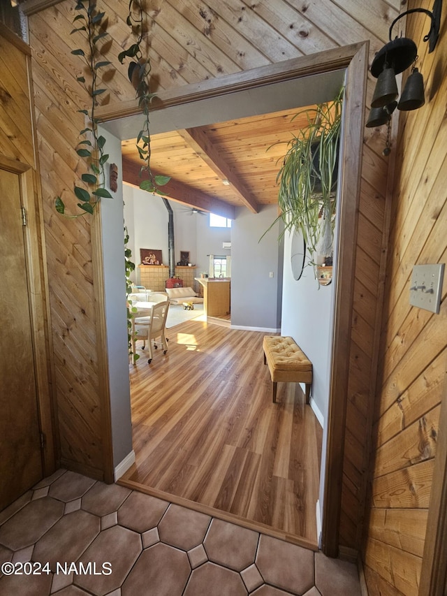 hallway featuring wooden ceiling, wooden walls, and beamed ceiling