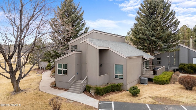 view of front of home with a shingled roof and central AC