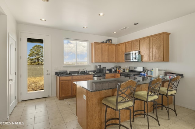 12361 Pegasus Rd, Bellemont, AZ 86015 - kitchen featuring stainless steel appliances, a peninsula, brown cabinets, a breakfast bar, and recessed lighting