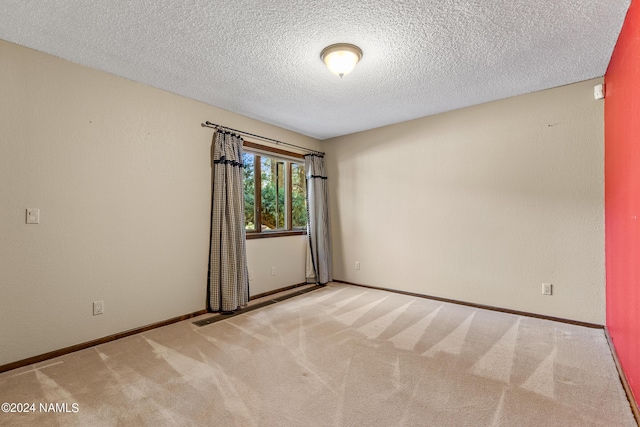 unfurnished room with light colored carpet and a textured ceiling