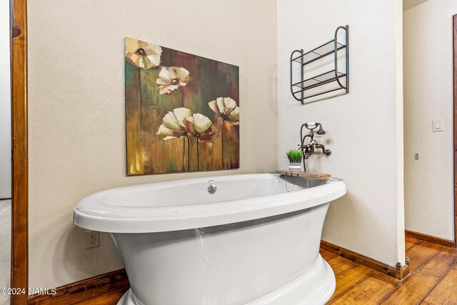 bathroom with a tub and hardwood / wood-style flooring