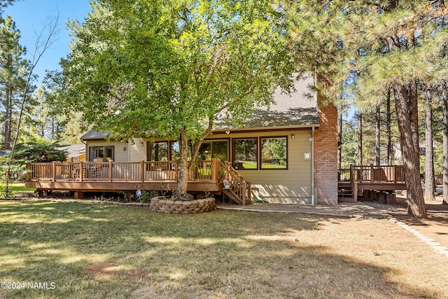 back of property with a deck and a lawn