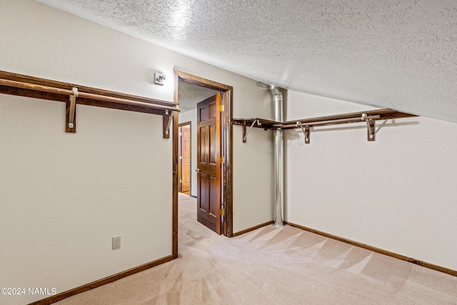 walk in closet with light carpet and vaulted ceiling