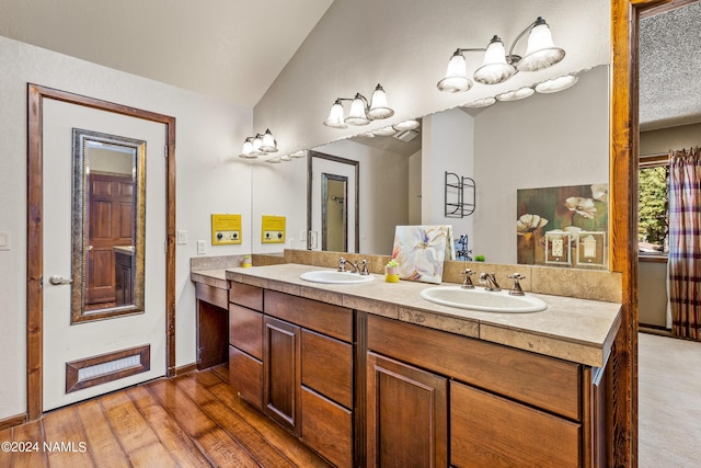 bathroom featuring hardwood / wood-style floors, lofted ceiling, and vanity