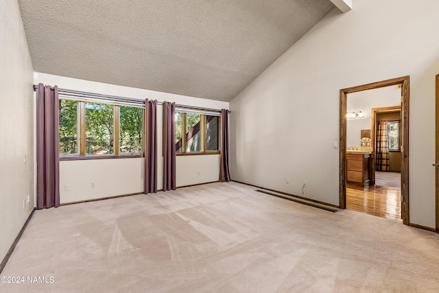 carpeted empty room featuring high vaulted ceiling