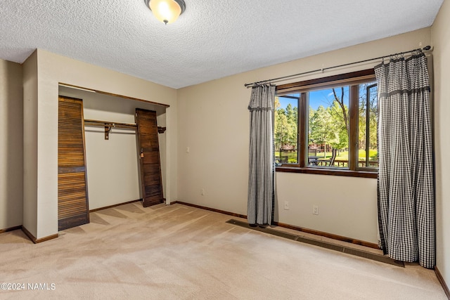 unfurnished bedroom featuring a closet, light colored carpet, and a textured ceiling