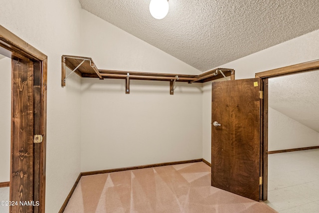 spacious closet with light colored carpet and vaulted ceiling