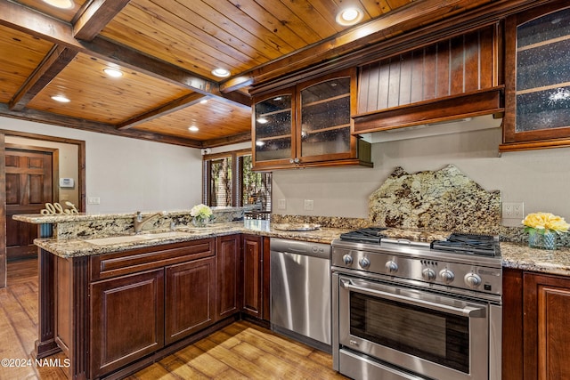 kitchen featuring light stone countertops, sink, appliances with stainless steel finishes, and kitchen peninsula