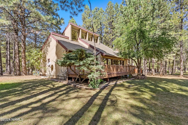 back of property featuring a wooden deck and a yard