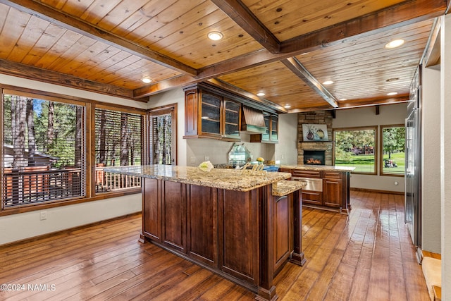 kitchen with light stone counters, wooden ceiling, hardwood / wood-style flooring, and a center island