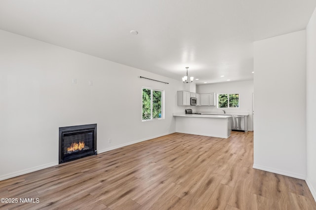 5026 E Retreat Cir, Flagstaff, AZ 86004 - unfurnished living room featuring recessed lighting, light wood finished floors, a chandelier, and a glass covered fireplace