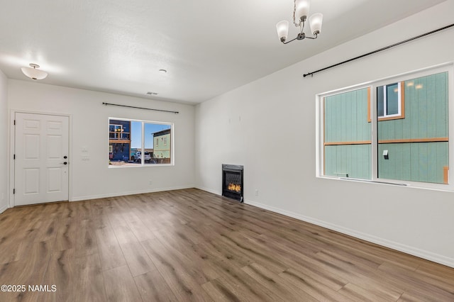 5026 E Retreat Cir, Flagstaff, AZ 86004 - unfurnished living room featuring wood finished floors, a chandelier, and a lit fireplace