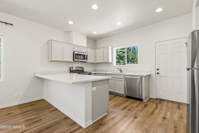 5026 E Retreat Cir, Flagstaff, AZ 86004 - kitchen with stainless steel appliances, light wood-style flooring, a peninsula, recessed lighting, and light countertops