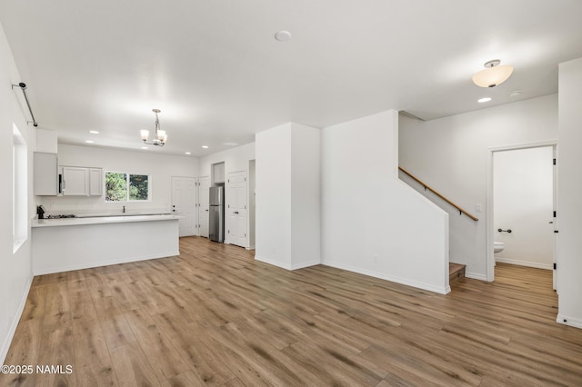 5026 E Retreat Cir, Flagstaff, AZ 86004 - unfurnished living room with a chandelier, light wood-type flooring, stairway, and recessed lighting